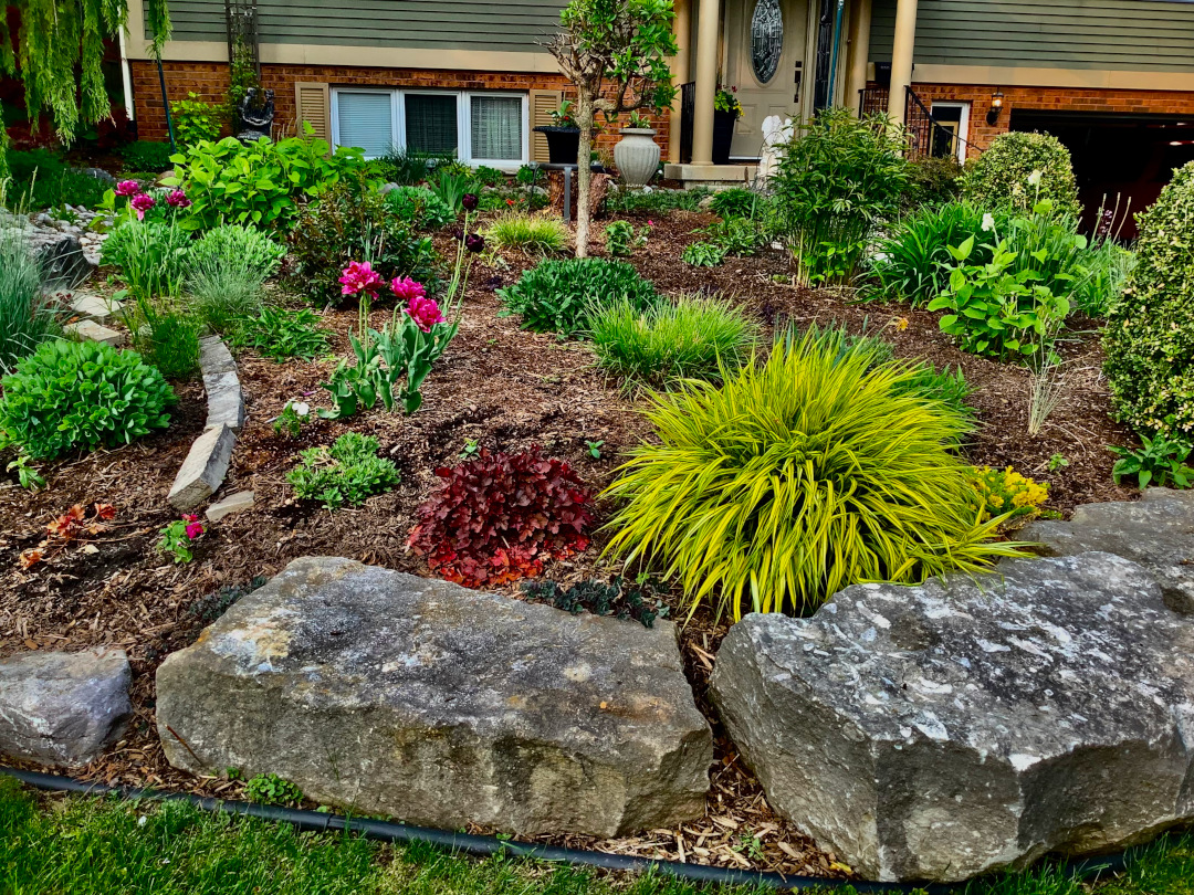 front yard garden bed with large stones around the edge